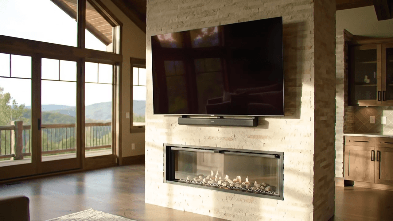 Wall-mounted TV and soundbar above a linear fireplace in a mountain home with a Blue Ridge view
